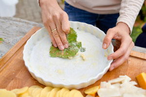 Prepare a gratin of potatoes, pumpkin and Jerusalem artichokes, grease the quiche form with butter and garlic in the vine leaf Prepare a gratin of potatoes, pumpkin and Jerusalem artichokes, grease the quiche form with butter and garlic in the vine leaf